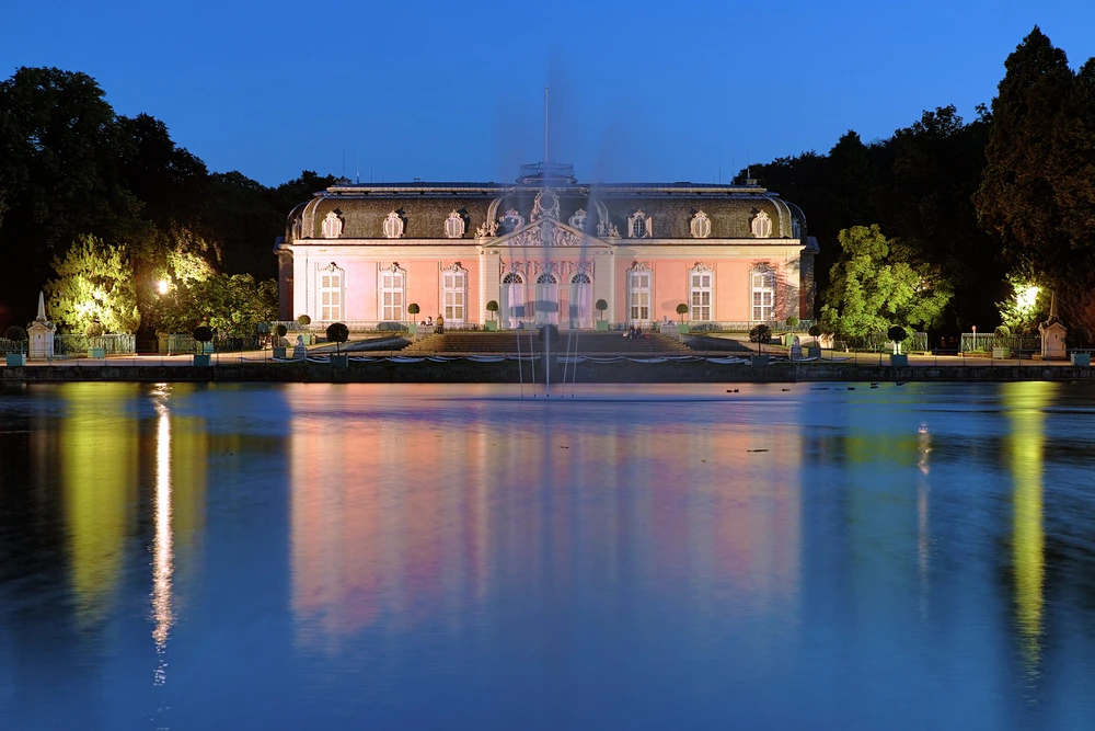Das Benrather Schloss beleuchtet bei Nacht vor See